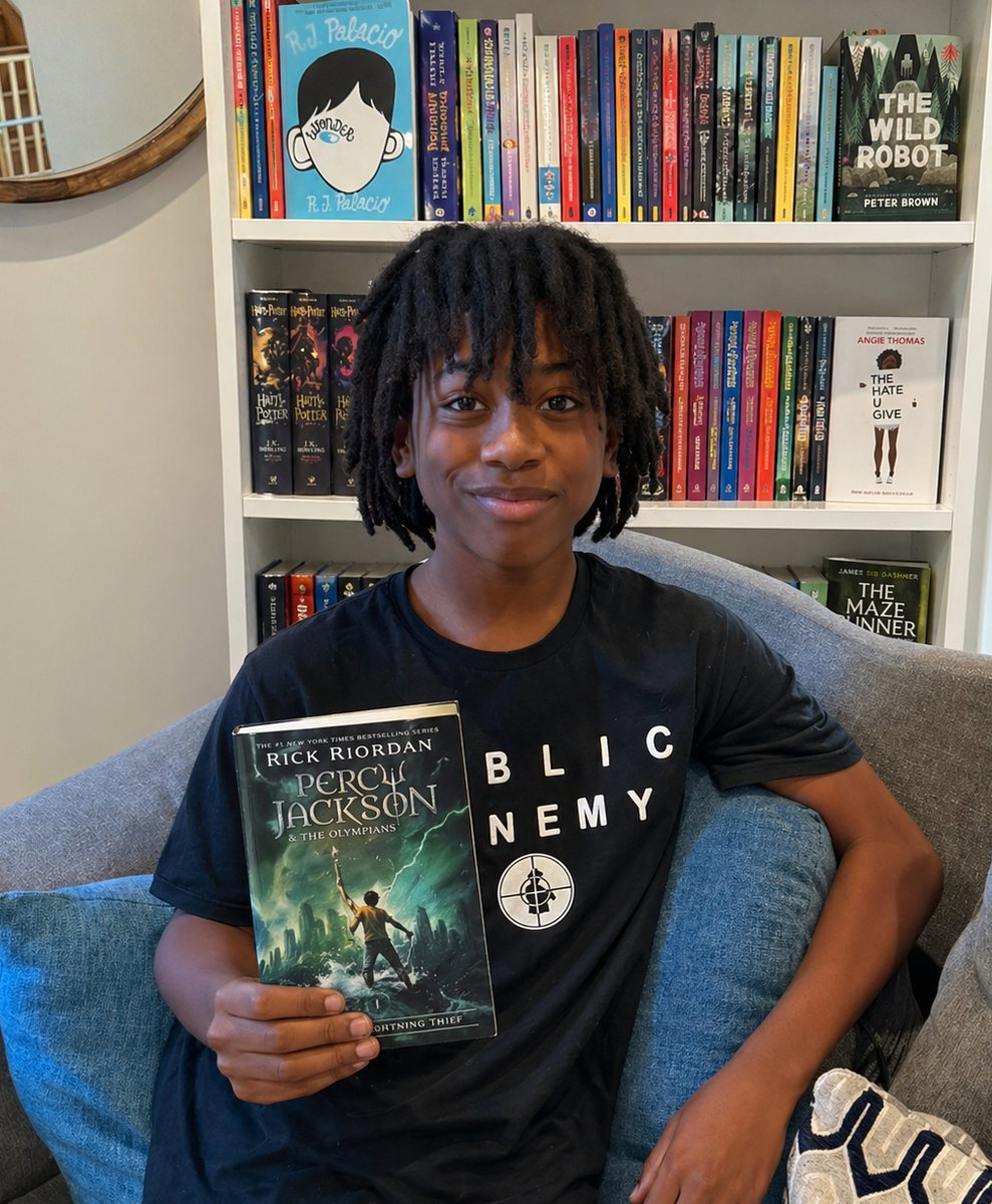 Bryson, founder of Bryson's Book Club, holding a Percy Jackson book in front of his bookshelf